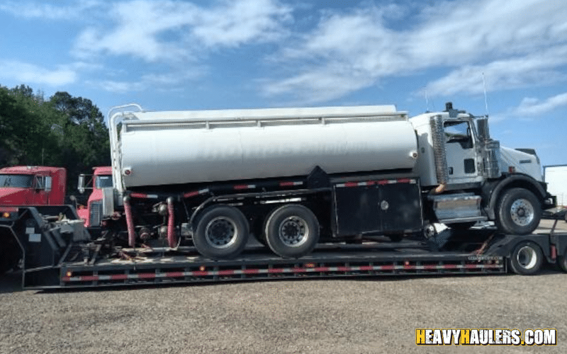 Transporting a tanker truck on a lowboy trailer.