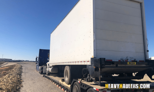 Shipping a box truck on a lowboy trailer.
