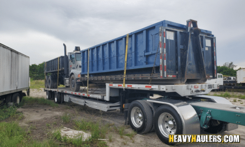 Transporting two roll off dumpsters on a step deck trailer.