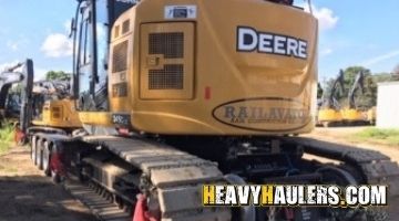 Loading a John Deere excavator on an RGN trailer for transport.