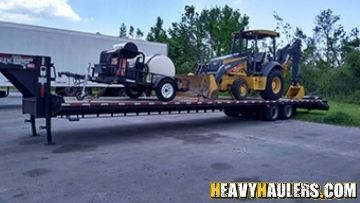 Loading a John Deere backhoe on a trailer.