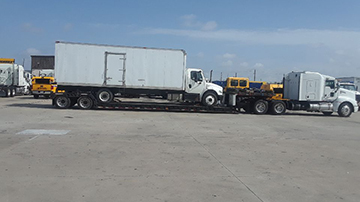 2014 Freightliner M2 box truck loaded on a RGN trailer