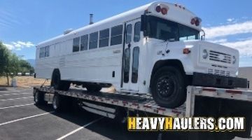 White school bus shipped on a trailer.
