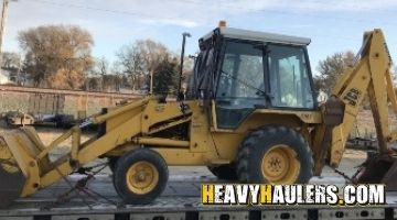 Loading a JCB loader backhoe on a trailer for transport.