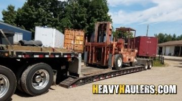 Transporting a forklift on a lowboy trailer.