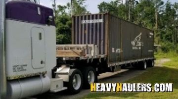 Forty foot container on a trailer being transported by a semi truck.