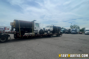 (2) Single axle dump trucks loaded on a step deck trailer.