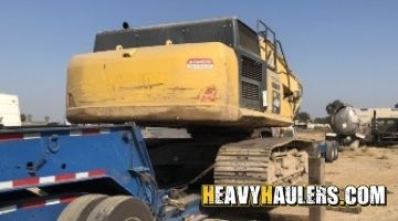 Loading a Komatsu excavator on a trailer for transport.