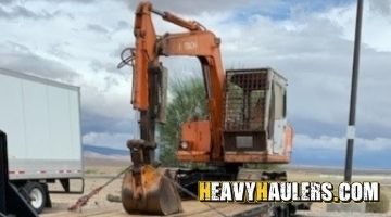 Strapping a Hitachi excavator on a trailer for transport.
