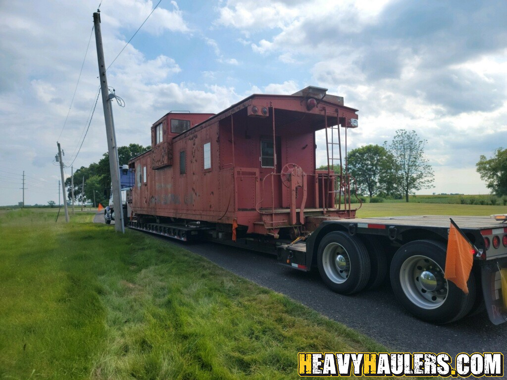 Shipping a caboose on a lowboy trailer.
