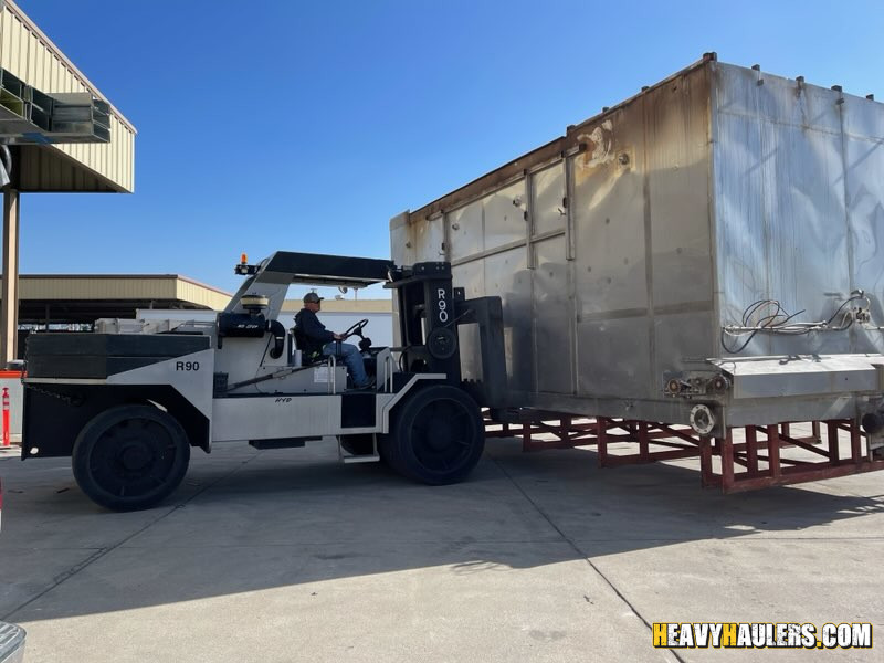 Forklift lifting a spray dryer for loading.