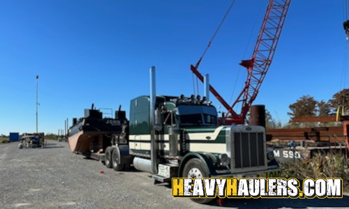 Transporting an oversize push barge on a lowboy trailer.