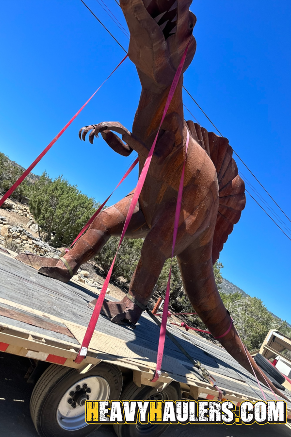 Steel dinosaur shipped on a trailer.
