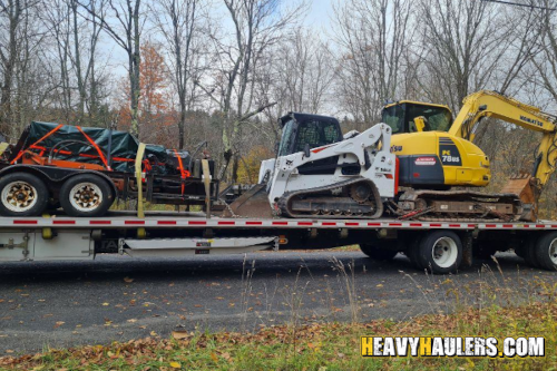 Construction equipment shipped on a flatbed utility trailer.