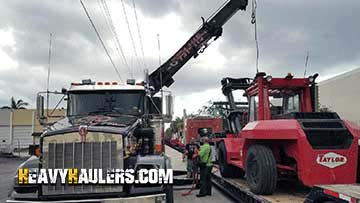 Loading a forklift on a trailer with cranes.