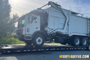 Loading a 2007 Mack MR 690 garbage truck on a trailer.