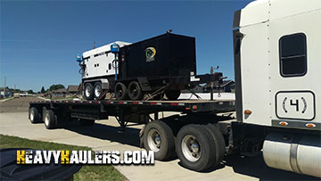 A Ingersol & Wacker towable generator loaded on a flatbed trailer