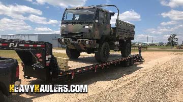 Loading a military truck on a lowboy trailer.