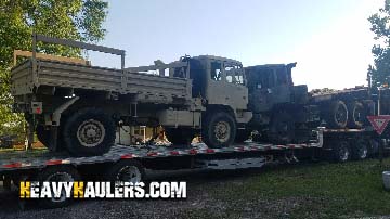 Hauling a military truck on a stepdeck trailer.