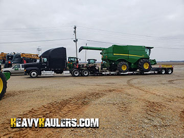 John Deere transported on trailer with outriggers
