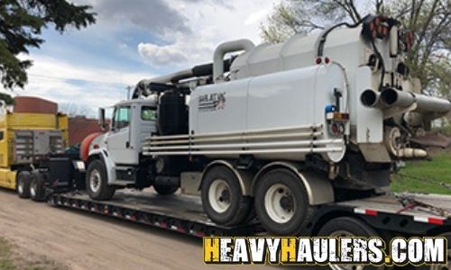 Hauling a Freightliner vacuum truck on an RGN trailer.