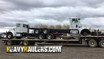 Shipping two semi trucks on a step deck trailer.