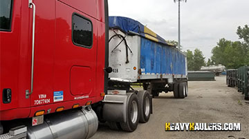 An aluminum end dump trailer being transported by using power only services