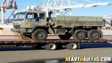 Shipping a military truck on a flatbed trailer.