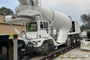 Transporting a concrete mixer truck on a trailer.