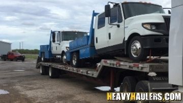 Transporting flatbed trucks on a step deck trailer.