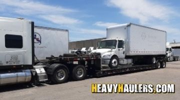 Shipping a box truck on a lowboy trailer.