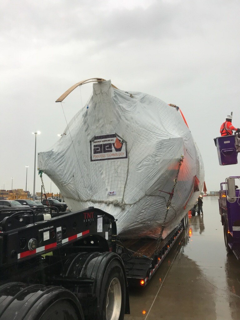 Shipping a tarped oversize boiler on a lowboy trailer.
